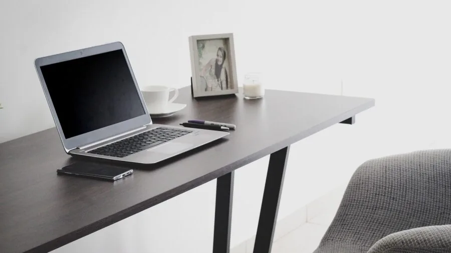 Person working on laptop at desk with spreadsheet displayed, focused on screen during work session