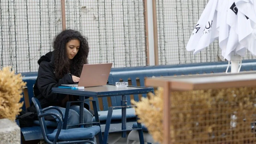 Person working on laptop at outdoor cafe with natural daylight
