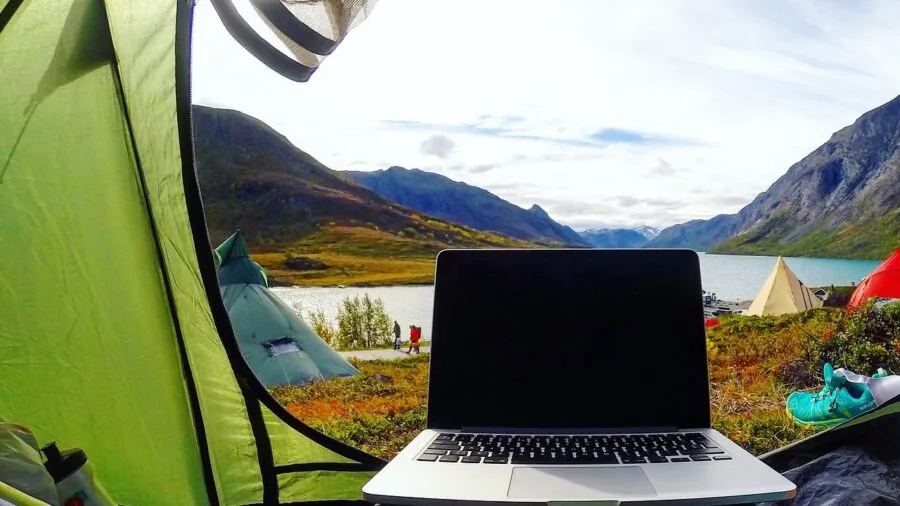Person working on laptop outdoors in natural setting, portable power concept