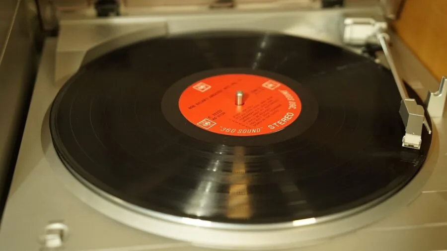 Person's hand pressing button on record turntable during listening session