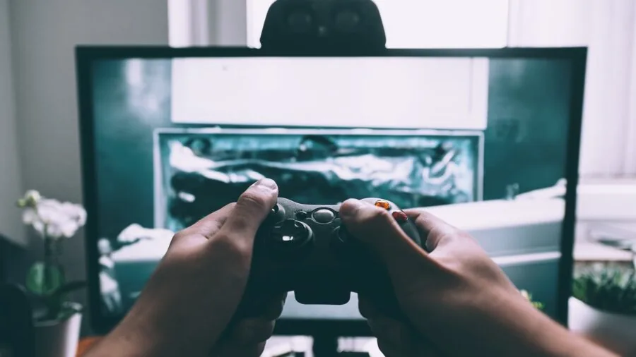 Person's hands holding a game controller while playing an intense racing video game