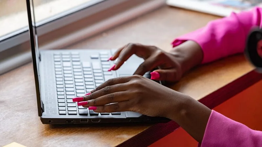 Person's hands typing on a mechanical keyboard at a wooden desk with natural lighting