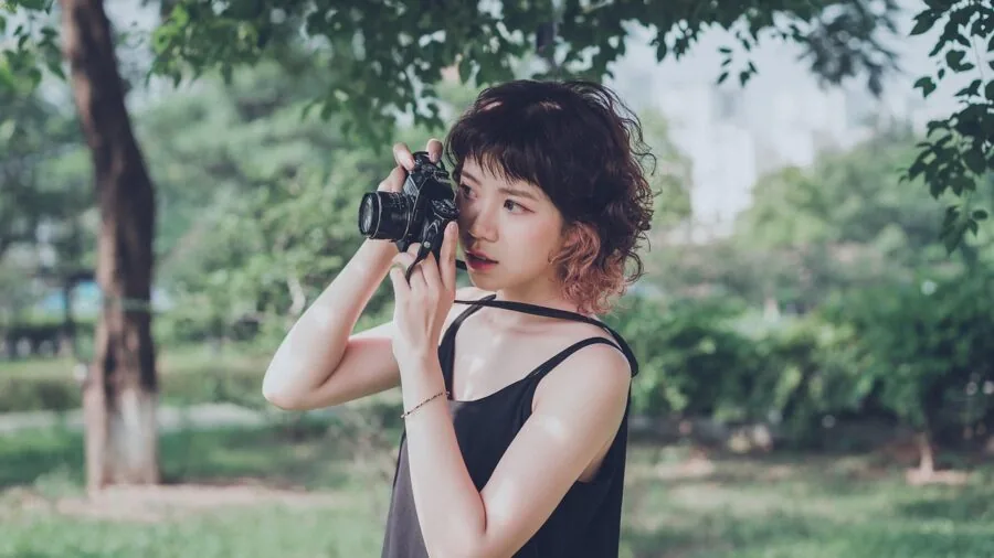Photographer adjusting camera lens filters while shooting landscape photography in natural outdoor setting