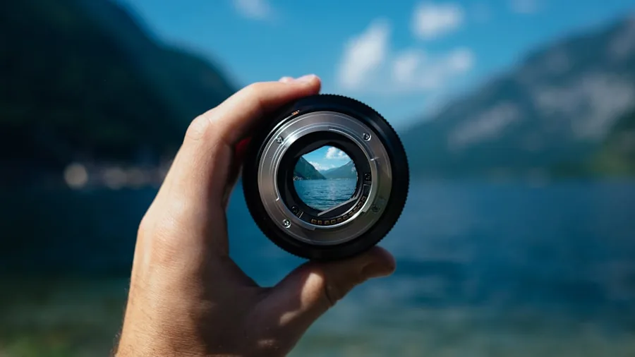 Photographer adjusting camera lens while capturing distant landscape scenery outdoors