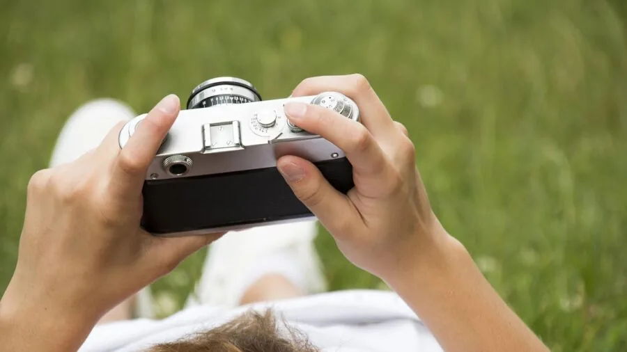 Photographer adjusting camera lens while shooting landscape photography in natural outdoor setting
