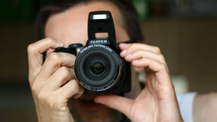 Photographer adjusting camera settings while composing a portrait with blurred background bokeh