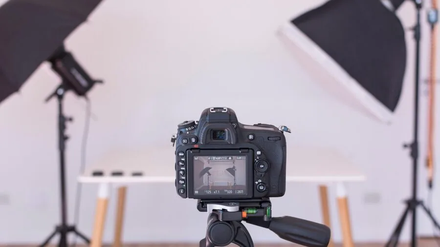 Photographer adjusting studio lighting equipment while setting up a professional photography session indoors