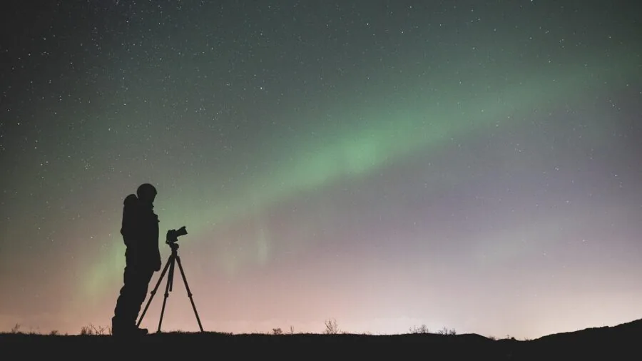 Photographer carefully adjusting tripod head while setting up outdoor camera equipment for shooting