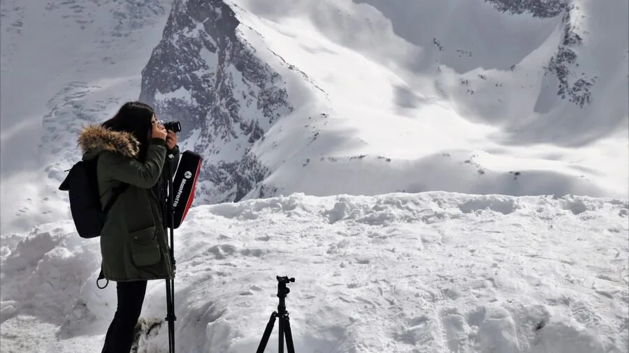 Photographer carrying gear while hiking through mountainous terrain at sunrise