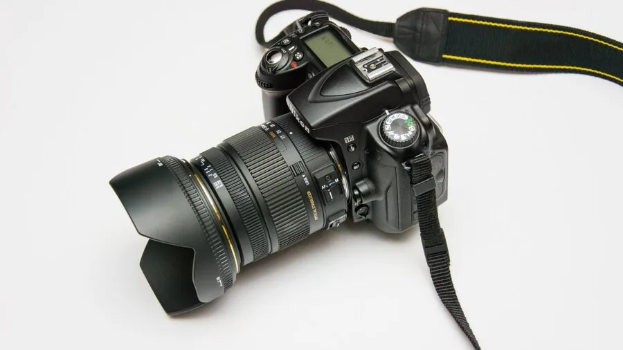Photographer examining camera lens mount compatibility with equipment on wooden surface