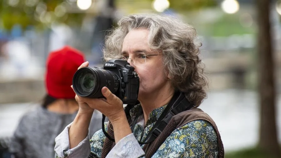 Photographer examining various camera lenses and equipment laid out on a wooden table