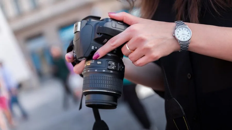 Photographer holding professional camera with zoom lens in outdoor natural setting