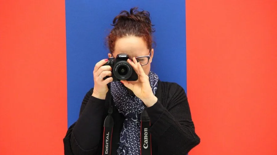Photographer in natural setting composing a landscape shot with zoom lens camera