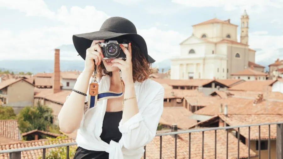 Photographer manually focusing camera while composing landscape shot during golden hour