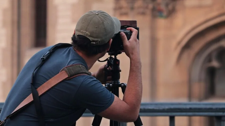 Photographer reviewing camera lenses and bodies outdoors in natural lighting