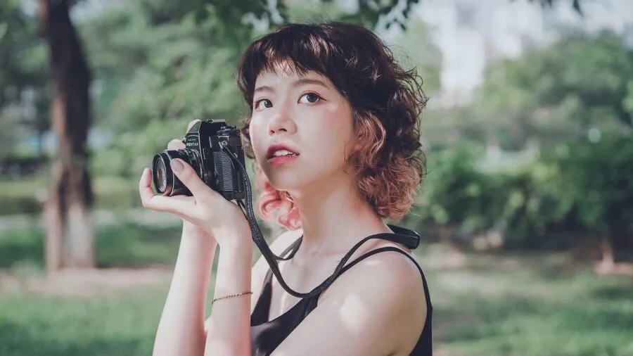Photographer reviewing camera lenses and equipment in natural outdoor setting