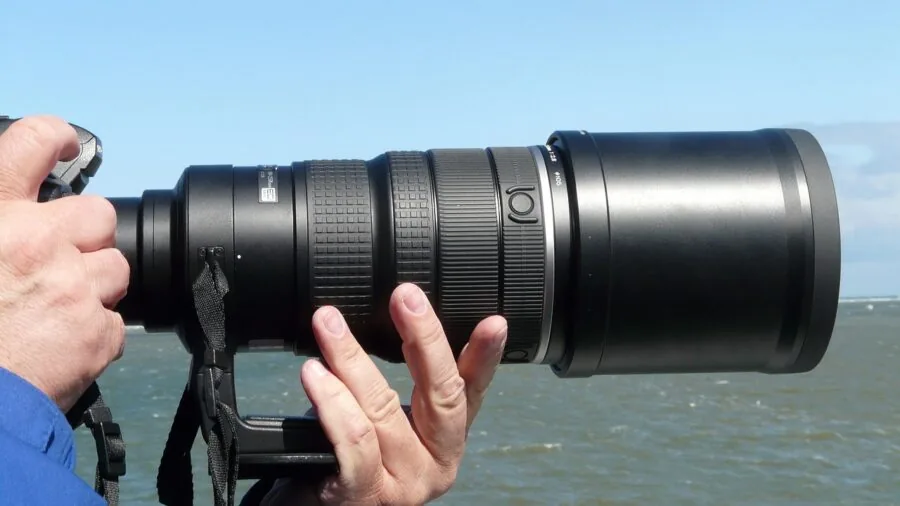 Photographer with telephoto lens demonstrating stable camera handling technique