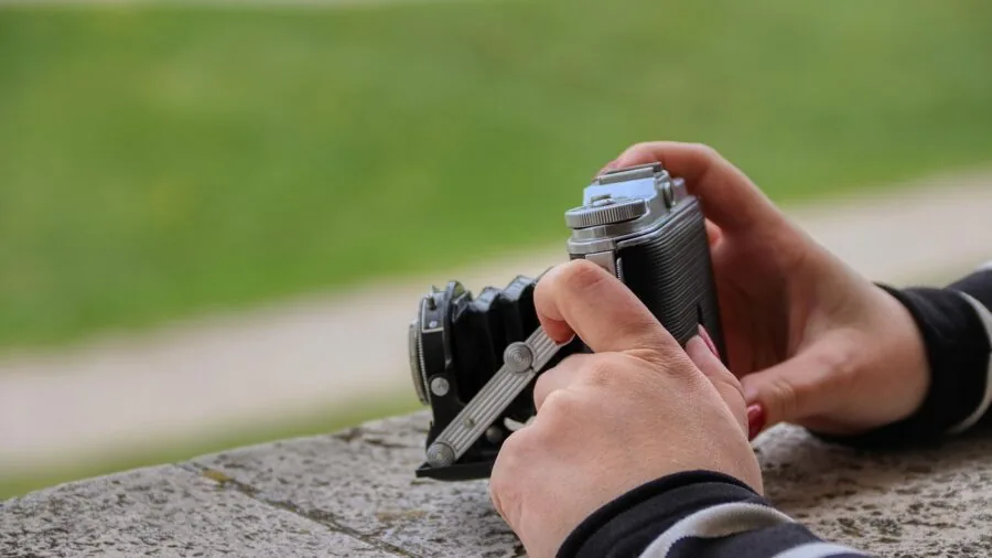 Photographer's hands adjusting camera controls and settings during outdoor shoot