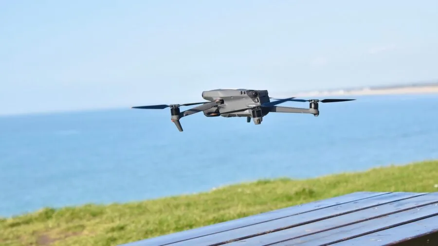 Pilot operating drone controller while flying over scenic terrain with live video transmission