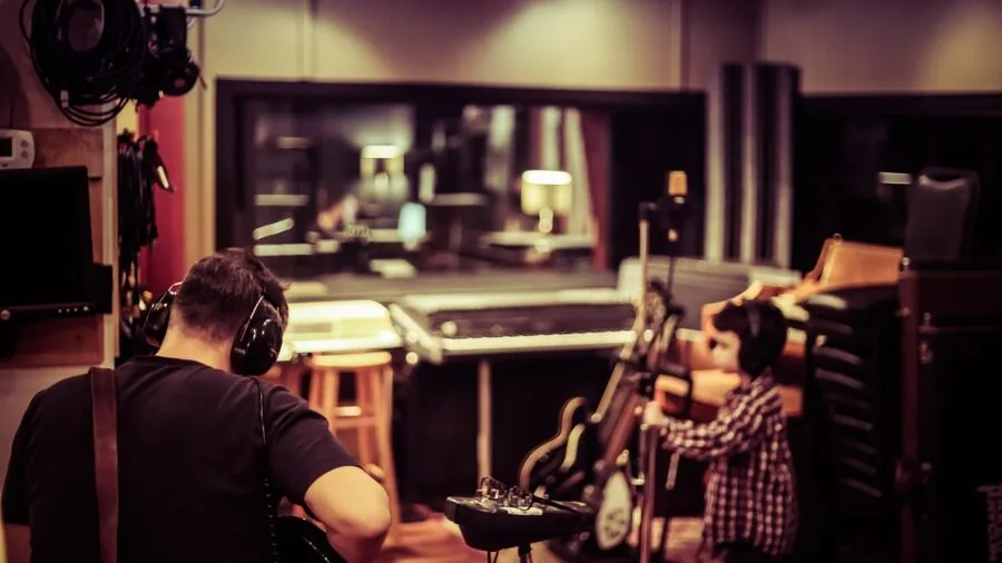 Professional audio engineer working at mixing console in modern recording studio with headphones
