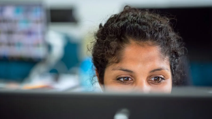 Professional focused on detailed work at a desktop computer setup in a modern workspace