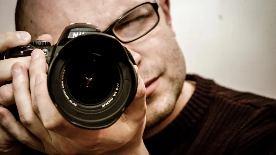 Professional photographer adjusting camera settings during an indoor portrait session with natural window light