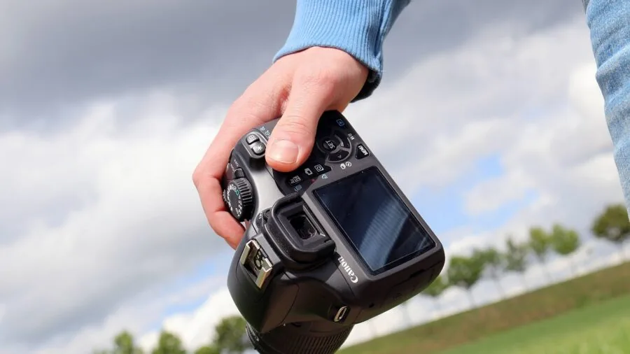 Professional photographer holding mirrorless camera while shooting outdoors in natural light