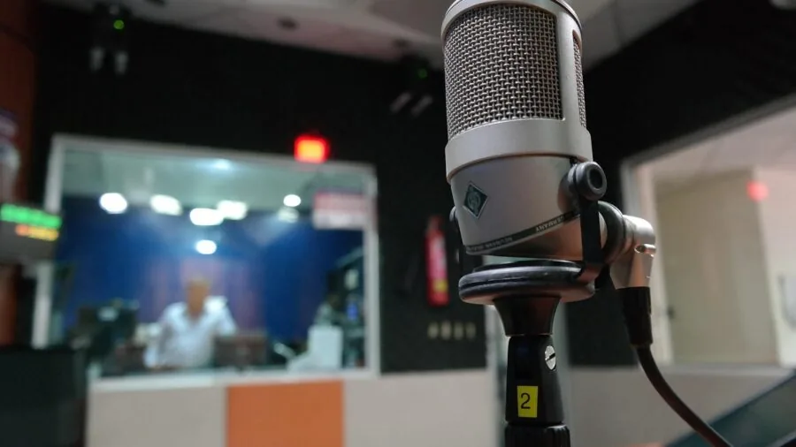Professional vocalist performing at microphone in home recording studio setup