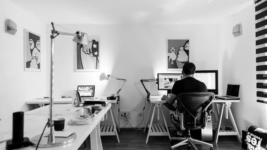 Professional working at desk with dual monitors displaying data and documents