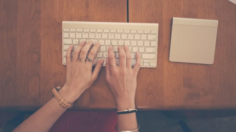 Professional working at desk with mechanical keyboard and Mac computer in modern home office setup