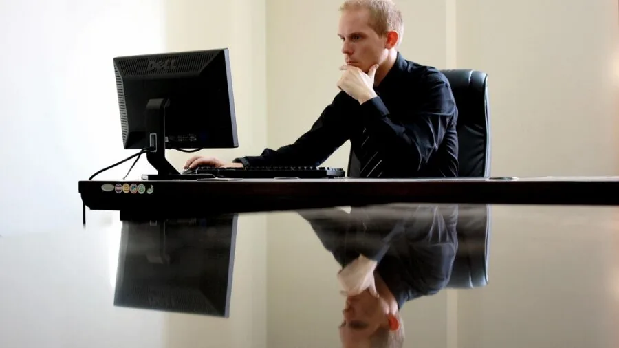 Professional working at desk with multiple external monitors and cables in modern workspace