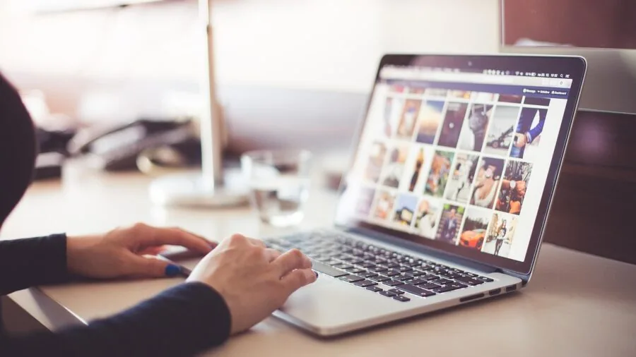 Professional working at laptop with focus on hands typing on keyboard at desk