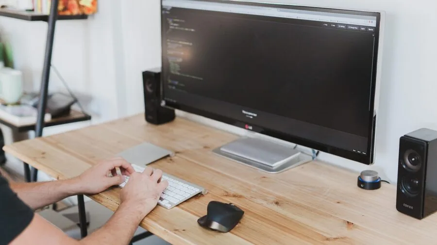 Professional working at organized desk with computer setup in modern office environment