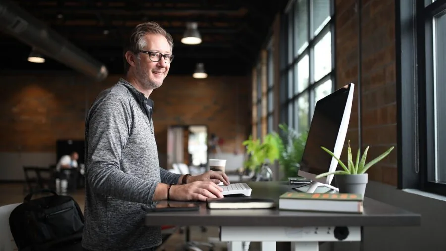 Professional working at organized desk with multiple monitors in modern office environment