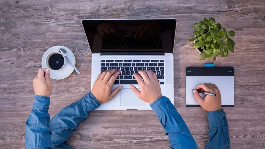 Professional working on multiple digital tasks simultaneously at desk with various devices