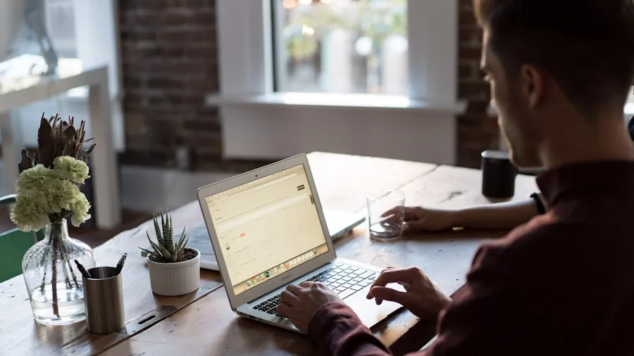 Professional workspace with laptop, multiple windows open, person working at organized desk with coffee