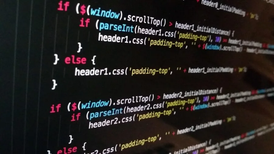 Programmer coding at desk with multiple monitors in home office environment