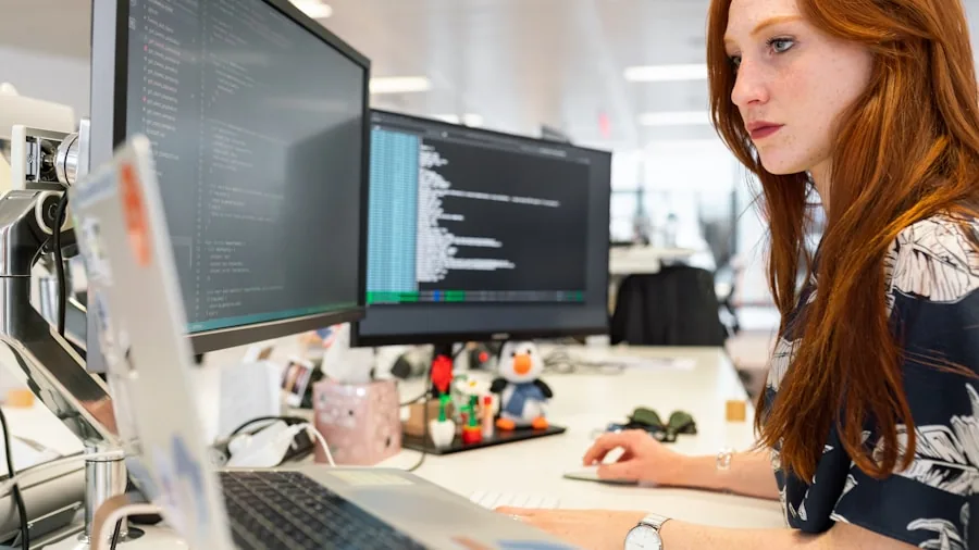Programmer focused on laptop with multiple monitors during intensive coding session