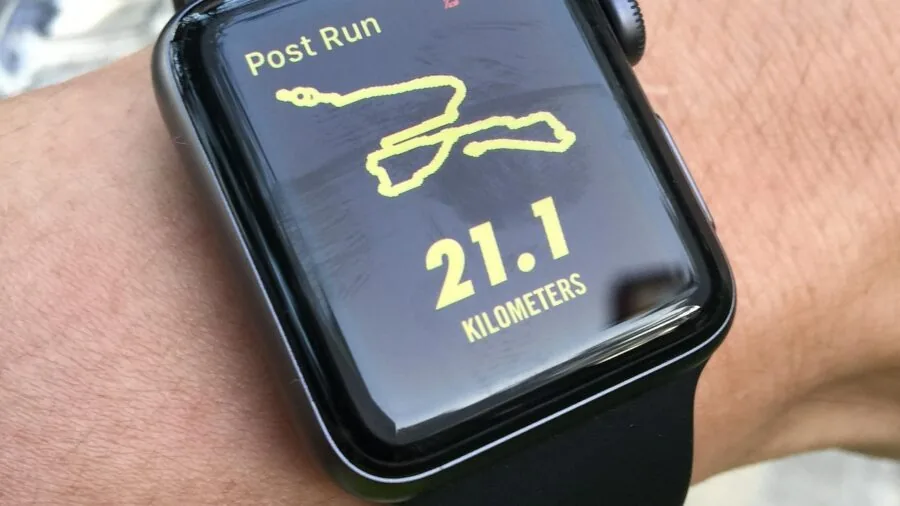 Runner wearing fitness tracker on wrist during outdoor running session on path