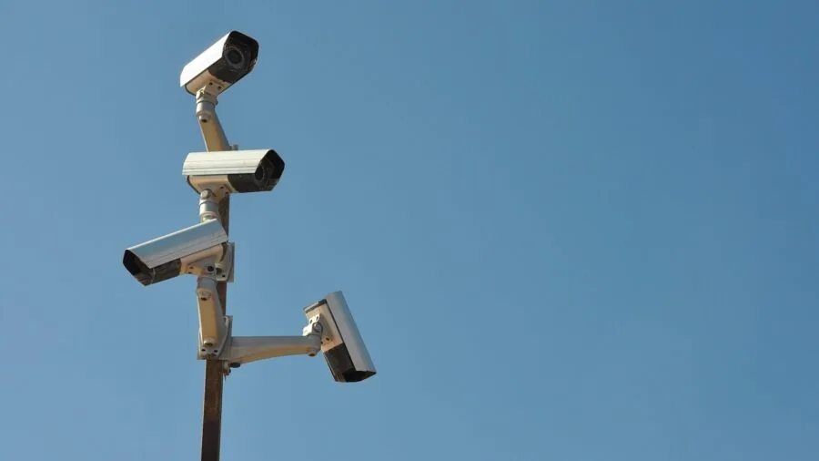 Security professional monitoring multiple camera feeds on screens in a modern control room