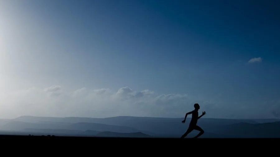 Solo creator jogging through scenic landscape while being filmed from above