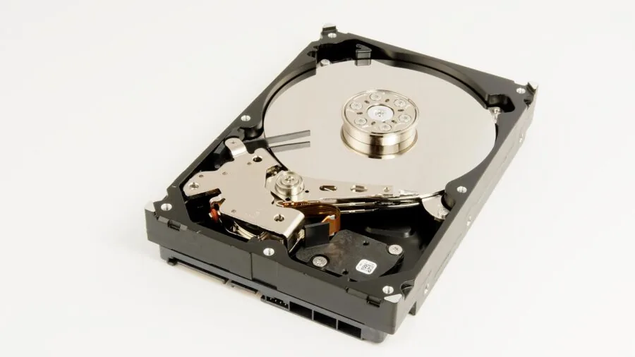 Someone arranging hard drives and computer components on a wooden desk with natural lighting