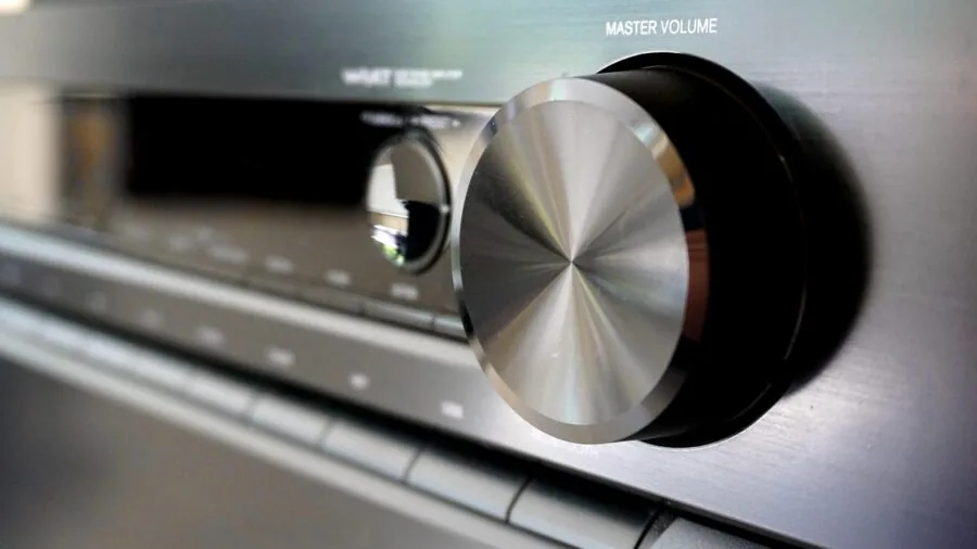 Someone carefully adjusting amplifier controls and settings on home audio equipment