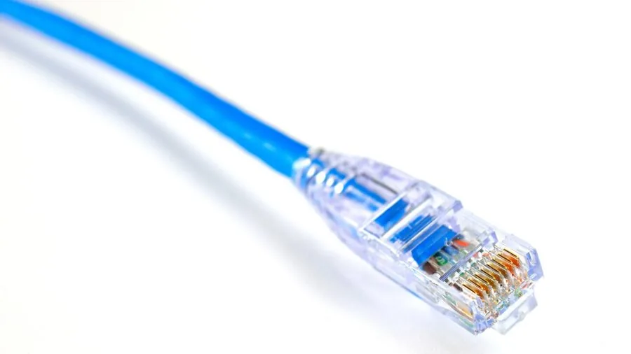 Someone plugging ethernet cables into network equipment during home office setup