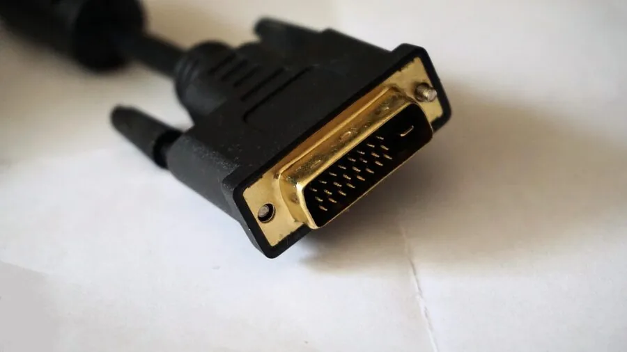 Someone plugging HDMI and DisplayPort cables into a monitor during computer setup in a home office environment