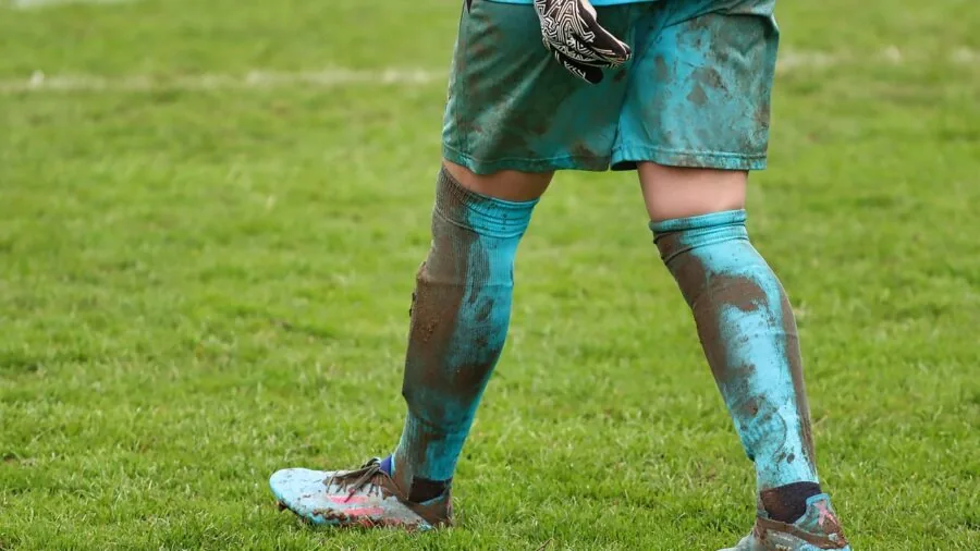 Sports gear and equipment in muddy outdoor field conditions showing durability and weather exposure