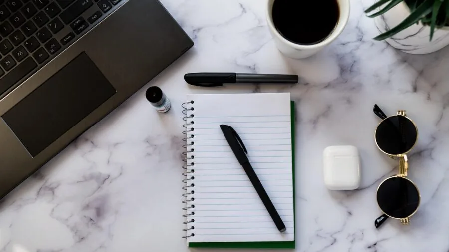 Student focused on laptop while researching and taking notes at desk during study session