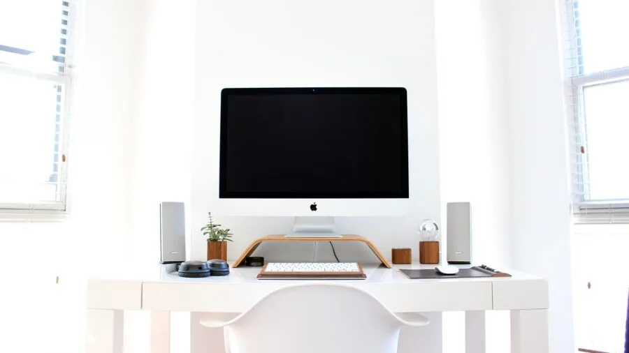 Student studying at desk with dual monitors and tower PC setup in dorm room