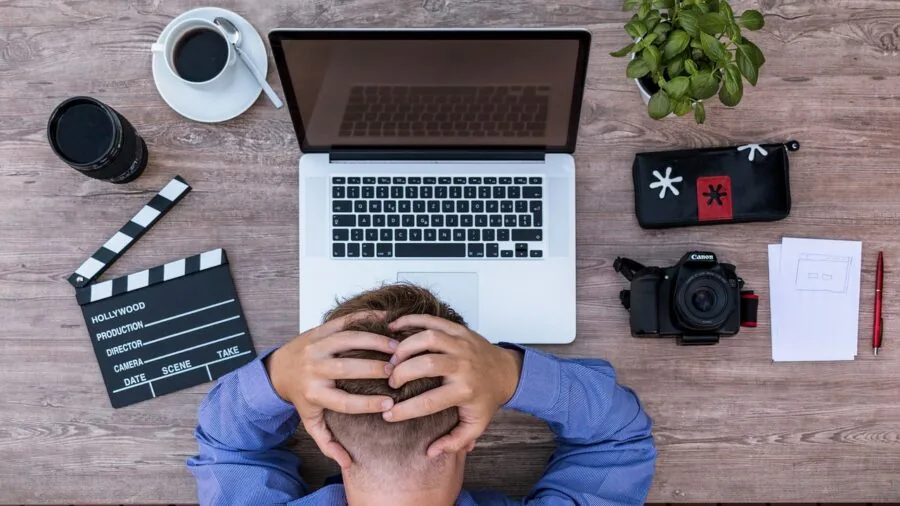 Student working at desk looking frustrated while connecting cables to laptop