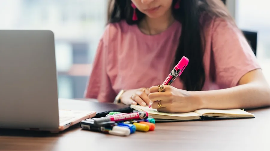 student writing notes while studying with technology